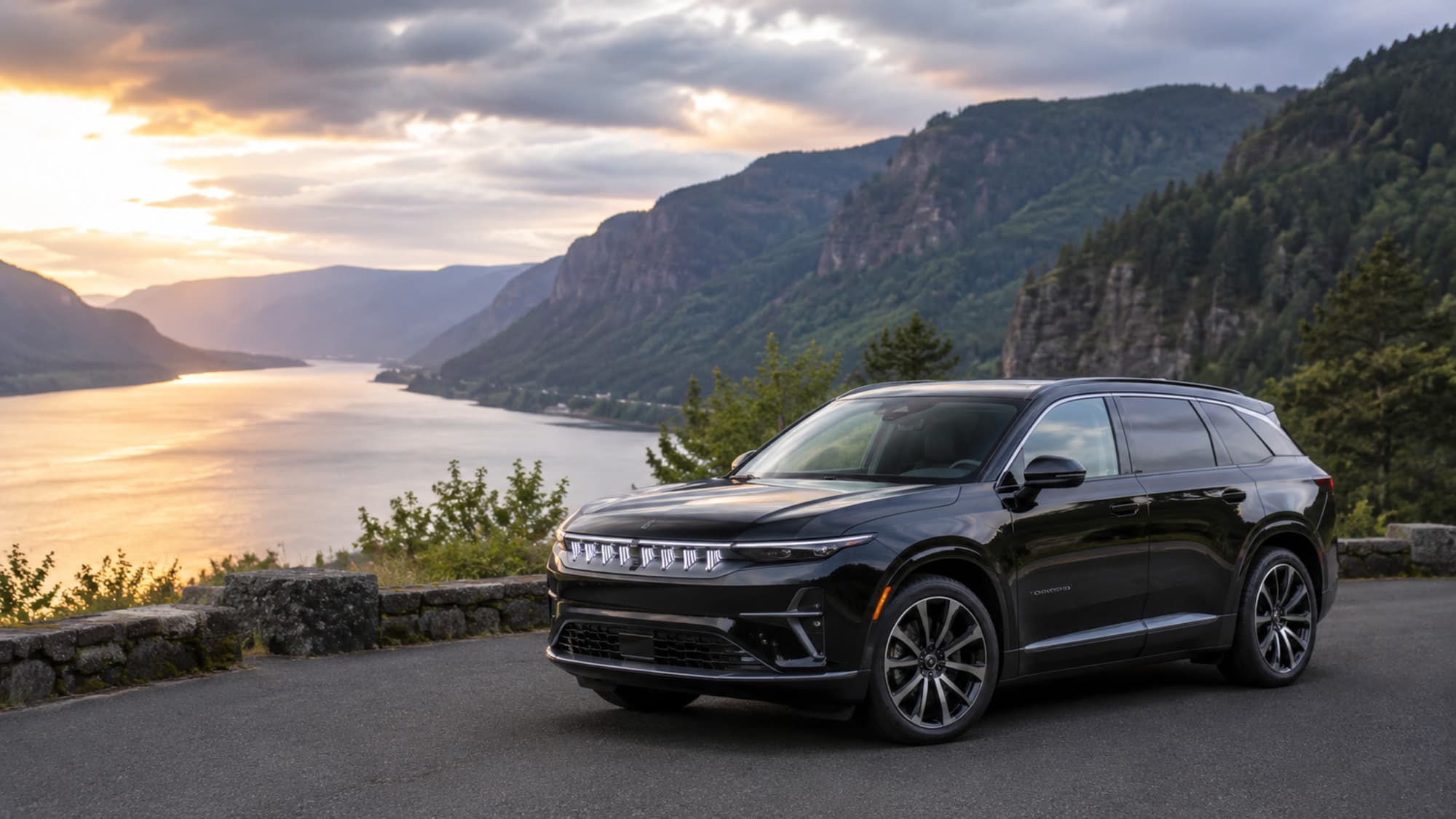 A black Jeep Wagoneer S on a river-gorge overlook at sunset